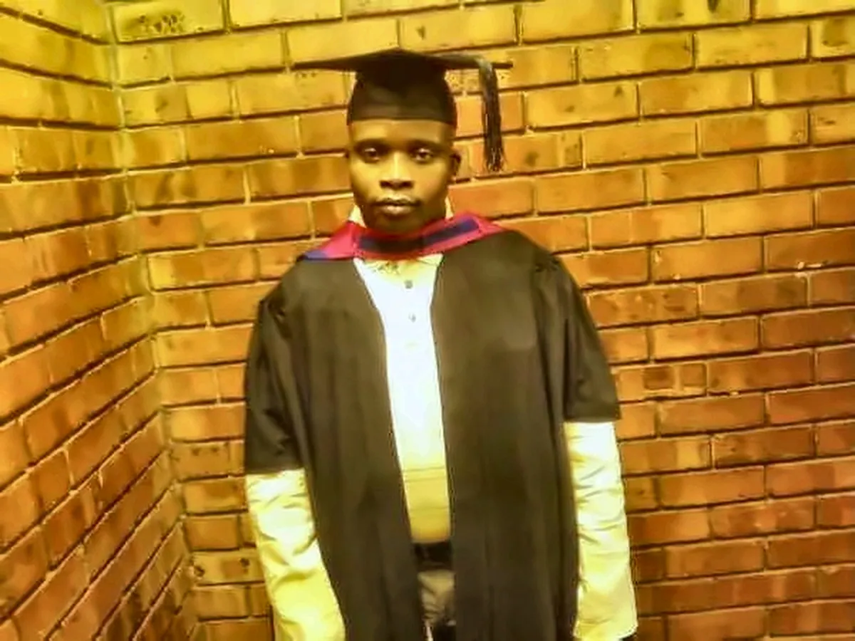 Professional wearing graduation regalia at a brick building